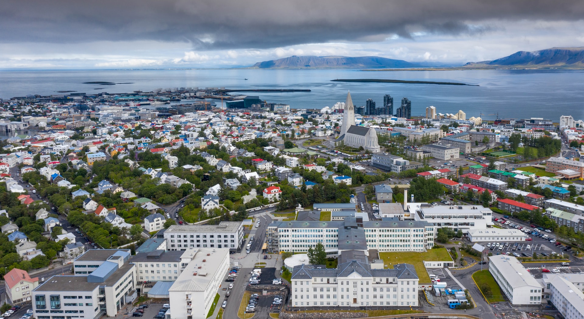 Image description: Aerial view of Reykjavik, the capital of Iceland, including its leafy suburbs and Hallgrímskirkja, a tall Lutheran church. End of alt text.